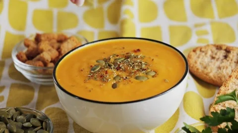 On the table is pumpkin cream soup, served with croutons, pumpkin seeds and Stock-Footage 335690434