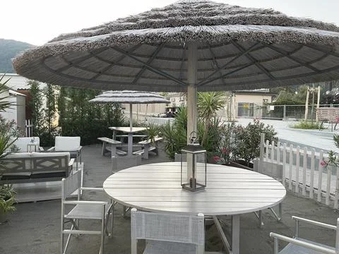 Table with reed umbrella for dinner. Relax area. Vacation and food. Design and Stock Photos