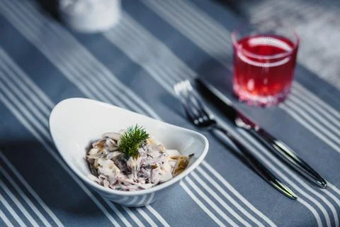 Table in the restaurant. On the table is a salad in a white plate, a knife, a Stockfoto's
