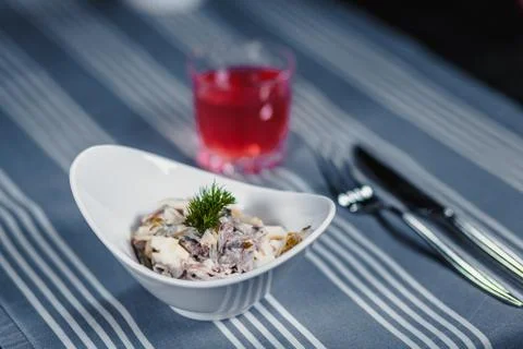 Table in the restaurant. On the table is a salad in a white plate, a knife, a Stock Photos