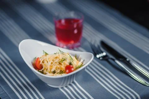 Table in the restaurant. On the table is a salad in a white plate, a knife, a Stock-Fotos