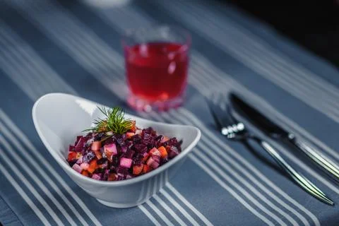Table in the restaurant. On the table is a salad in a white plate, a knife, a Stock Photos