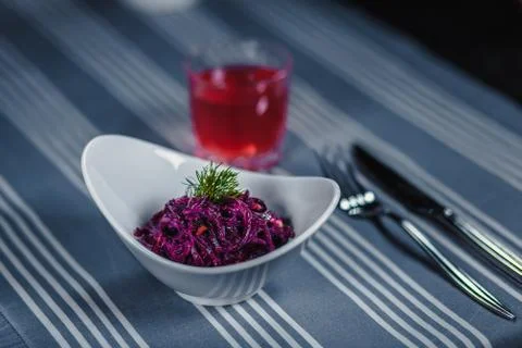 Table in the restaurant. On the table is a salad in a white plate, a knife, a Stockfoto's