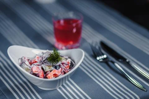 Table in the restaurant. On the table is a salad in a white plate, a knife, a Stock Photos