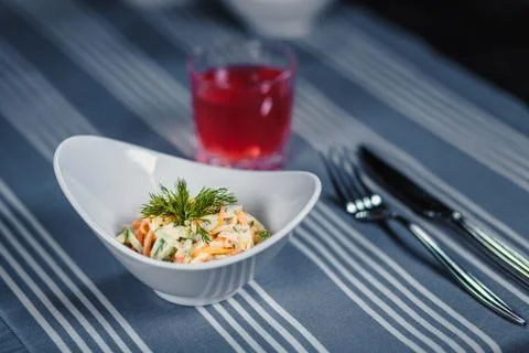 Table in the restaurant. On the table is a salad in a white plate, a knife, a Stock-Fotos