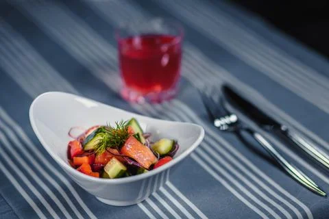 Table in the restaurant. On the table is a salad in a white plate, a knife, a Stockfoto's