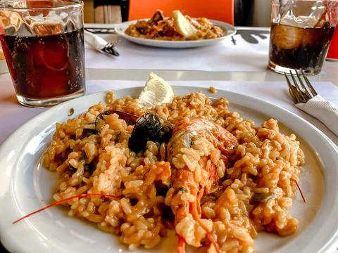 On the table in the restaurant there is a Spanish dish of paella cooked with Stock Photos