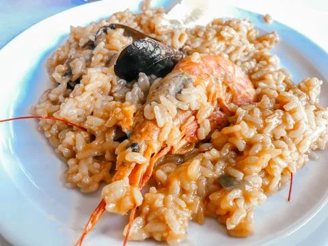 On the table in the restaurant there is a Spanish dish of paella cooked with Stock Photos