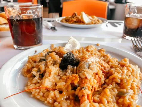 On the table in the restaurant there is a Spanish dish of paella cooked with Stock Photos