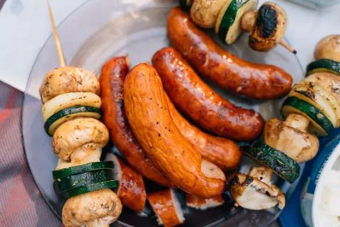 A table scape of summer picnic table with grilled sausages, mushrooms and Stock Photos