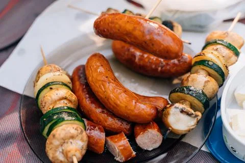 A table scape of summer picnic table with grilled sausages, mushrooms and Stock Photos