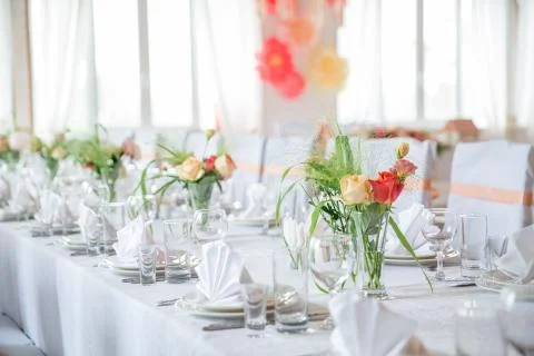 Table serving with dishes, glasses and flowers in hall 写真素材