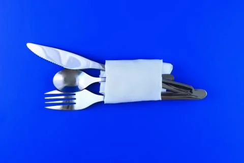 Table serving-knife,spoon,fork on blue backdrop. Stock Photos