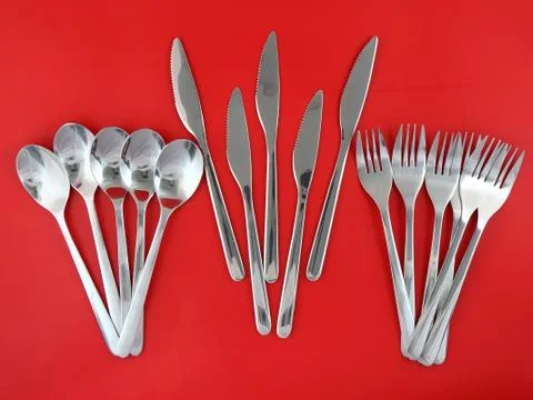 Table serving-knife,spoon,fork on red backdrop. Stock Photos