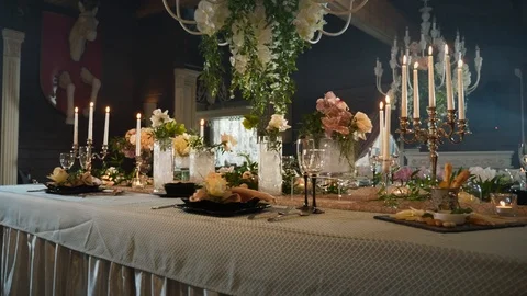 A table set with black arrows with food, wine glasses, flower vases Stock Footage 97718503