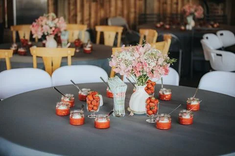 Table set for a celebration featuring jars of strawberry dessert, floral ar.. Stock Photos