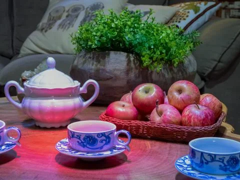 Table set with coffe cups, sugar bowl, and a basket of red apples Stock Photos