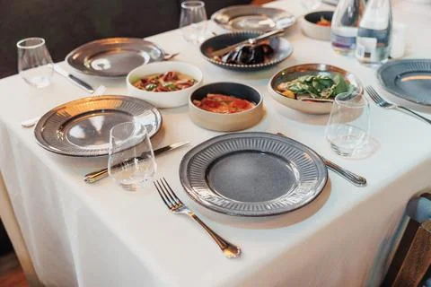 Table set for dining, featuring plates, glasses, and food bowls Stock Photos