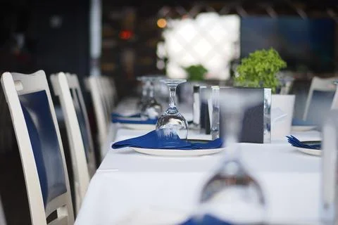 Table set for dinner at a restaurant with blue napkins Stock Photos