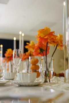 A table is set for an event with orange flowers, candles, and glassware. The  Stock Photos