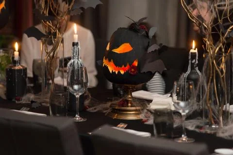 Table set for Halloween dinner. Served holiday table with candles and pumpkin Stock Photos