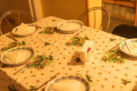A table is set with holly-patterned linens ready for a holiday meal. Stock Photos