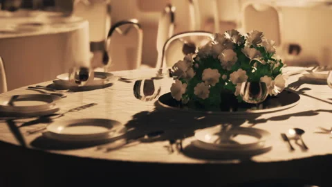 Table set for a meal with flowers in a dining area during an event Stock Footage 344099619