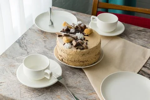 The table is set for tea: tea cups and saucers and a sponge cake with butterc Stock Photos