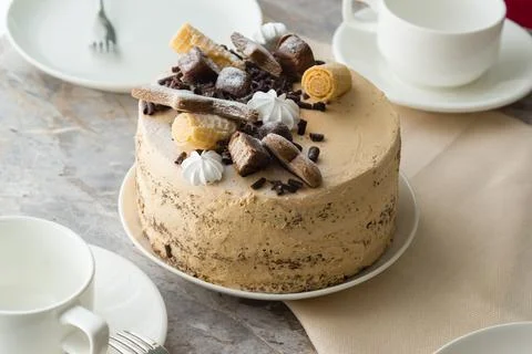 The table is set for tea: tea cups and saucers and a sponge cake with butterc Stock Photos