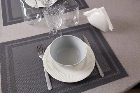 A table is set with a white plate, a gray bowl, glasses, and utensils, arra.. 写真素材