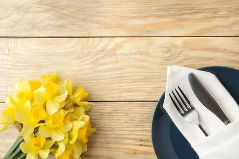 Table setting and spring flowers, yellow daffodils. Plate, knife and fork on Stock Photos