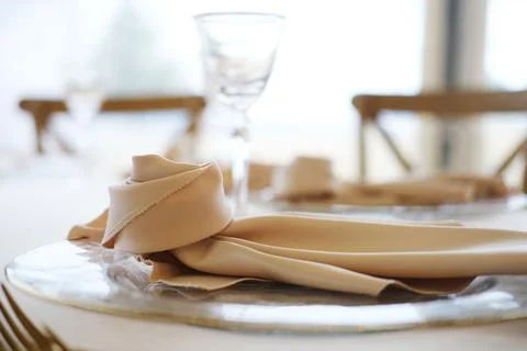 Table setting with beige napkin elegantly arranged on silver plate beside Фото