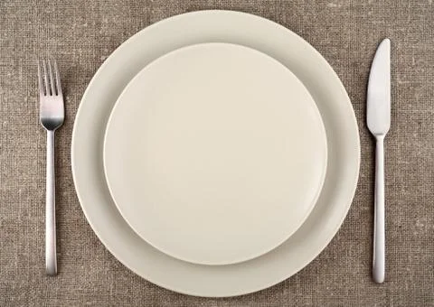 Table setting. Beige plate, fork, knife and beige linen tablecloth Stock Photos