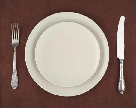 Table setting. Beige plates and vintage fork and knife on a brown linen tableclo Foto stock