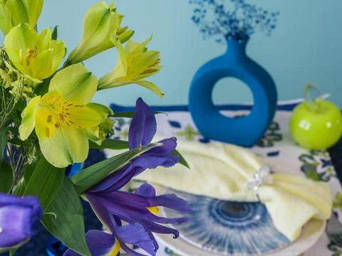 Table setting in blue and yellow colors. On a dark tablecloth a plate, a vase of Stock Photos