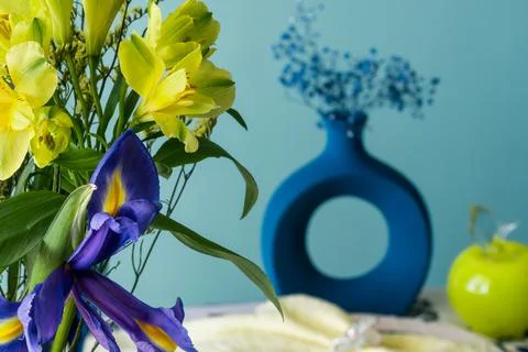 Table setting in blue and yellow colors. On a dark tablecloth a plate, a vase of Stock Photos