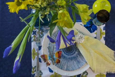 Table setting in blue and yellow colors. On a dark tablecloth a plate, a vase of Stock Photos