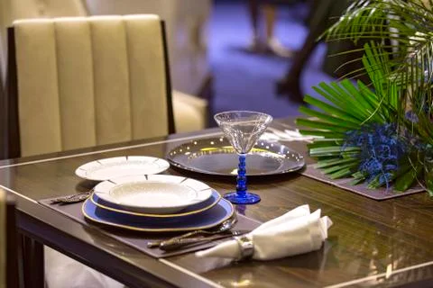 Table setting in blue color in the restaurant, plates, beautiful glasses, flo Stock Photos