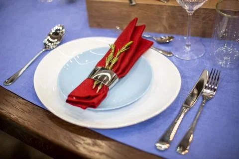 Table setting with a blue tablecloth, a white and blue plate, a red napkin in a Stock Photos