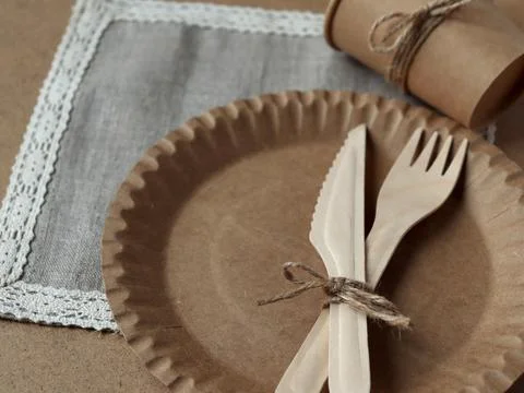 Table setting with brown paper plates, wooden utensils, and a small cup on a Fotos Stock