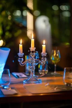 Table setting with candles, drinks, and a guest preparing drinks at a social Foto stock