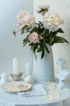 Table setting with a cup of tea and white peonies in a white ceramic jug Stock Photos