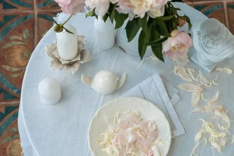 Table setting with a cup of tea and white peonies in a white ceramic jug Stock Photos