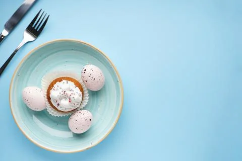 Table setting with cutlery and easter decorations on blue background. Top vie Stock Photos