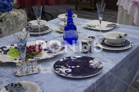 Table setting, dark blue plates, a blue tablecloth and a decanter of blue gla Stock Photos