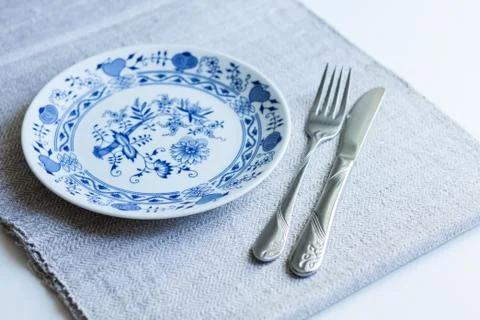 Table setting for dinner: a plate, a fork, a knife on a woven cloth napkin wi Stock Photos
