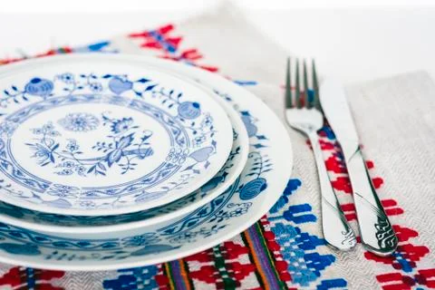 Table setting for dinner: white and blue plates, a fork, a knife on a woven c Stock Photos