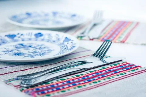 Table setting for dinner: white and blue plates, a fork, a knife on a woven c Stock Photos