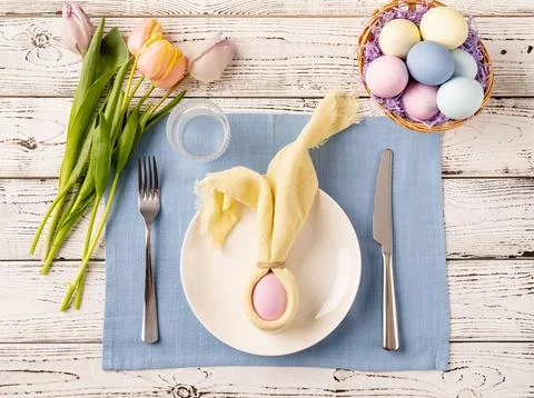 Table setting for Easter feast. Easter eggs, bunny, tulips and cutlery top .. Stock Photos