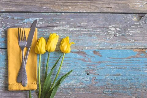 Table setting for easter holiday dinner; Fork and knife on yellow napkin an.. Stock Photos